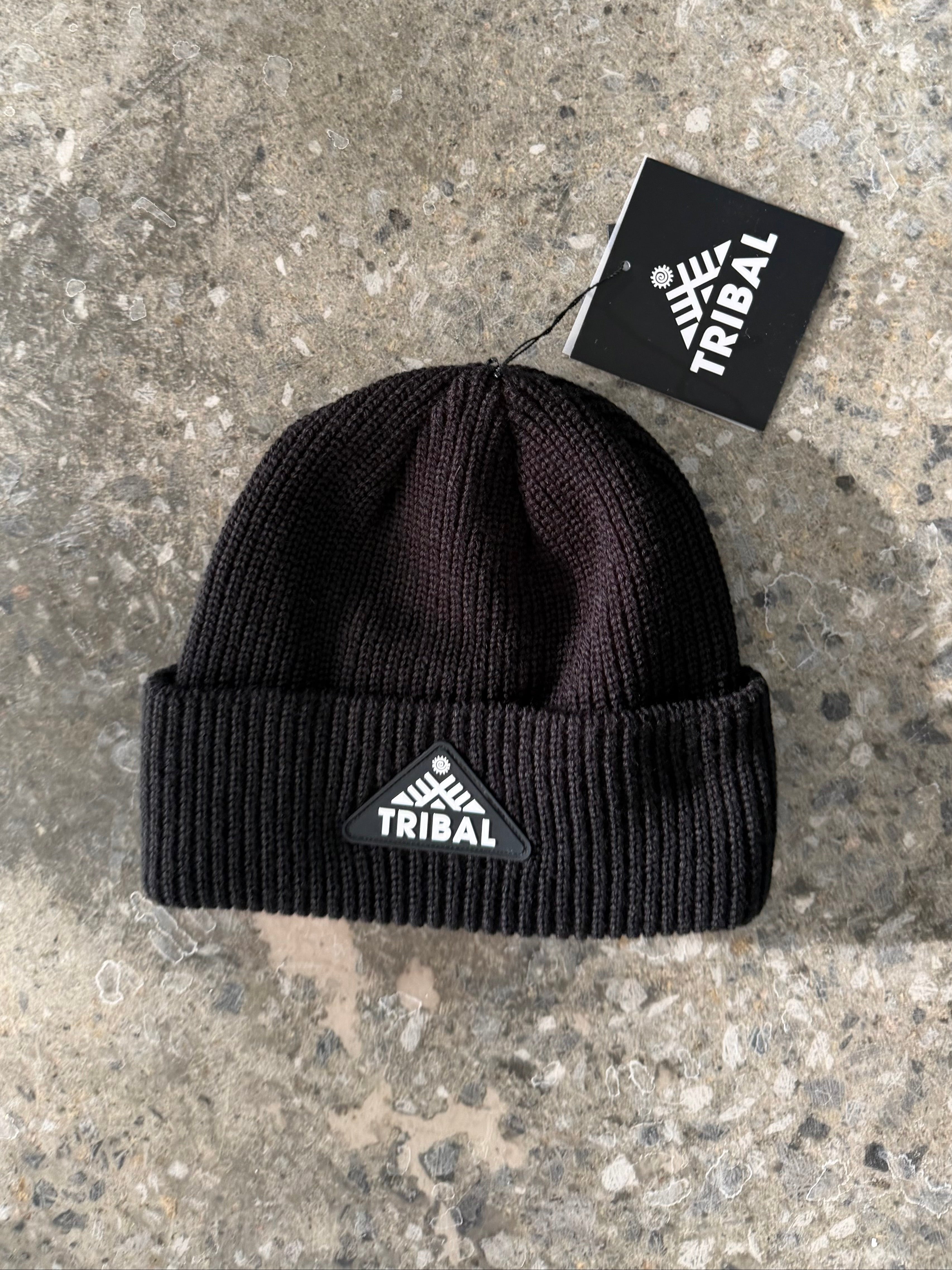 Black beanie with 'Tribal' logo on a concrete surface